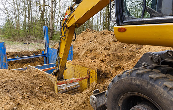 excavator removing dirt in a trench box